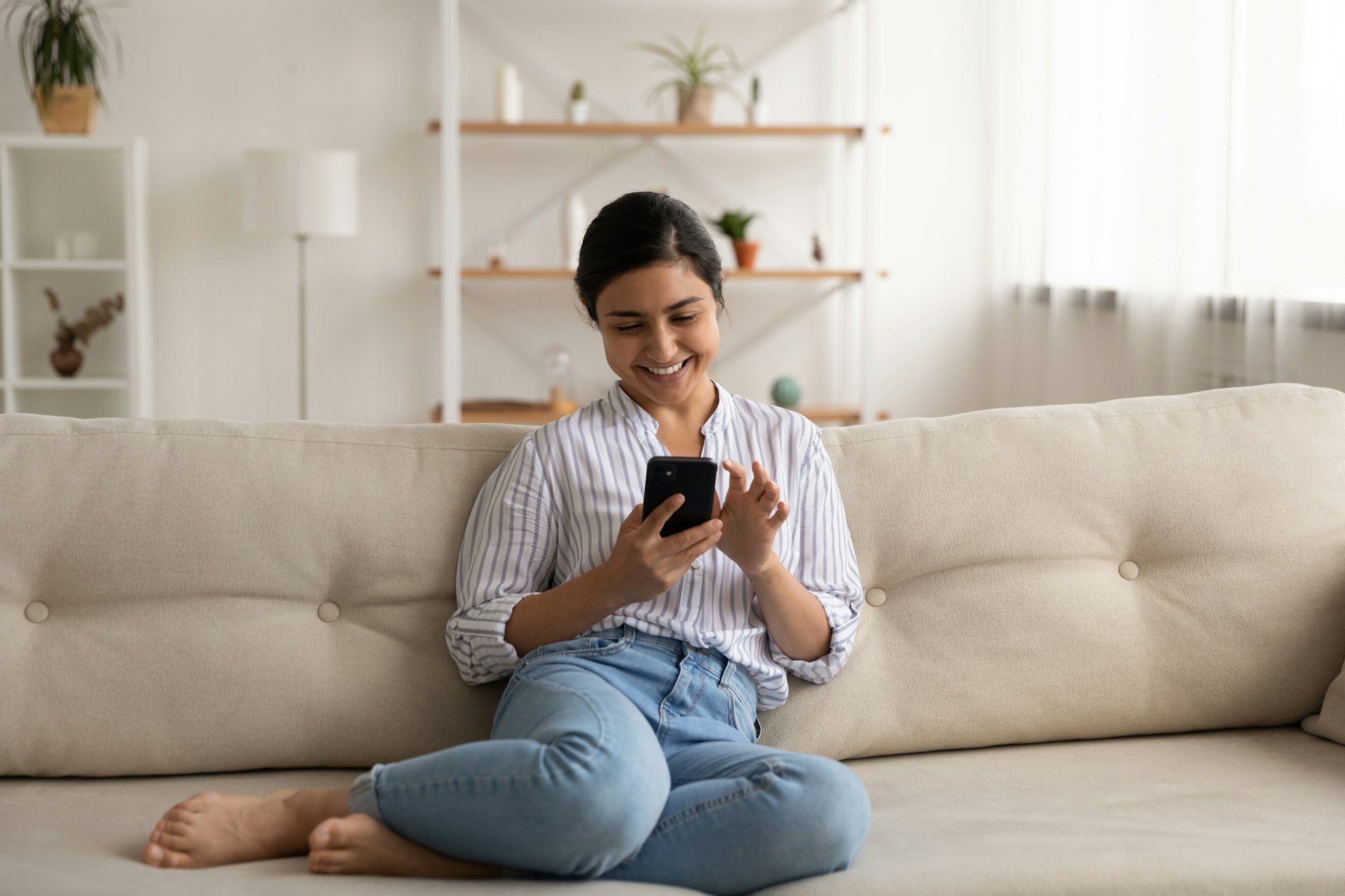 Property seller relaxing on the sofa smiling and checking their phone