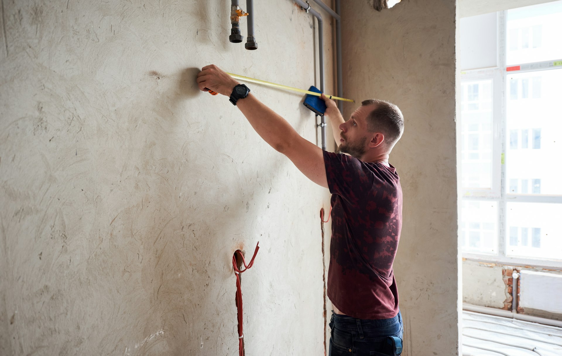 Professional tradesman measuring up the wall for a job