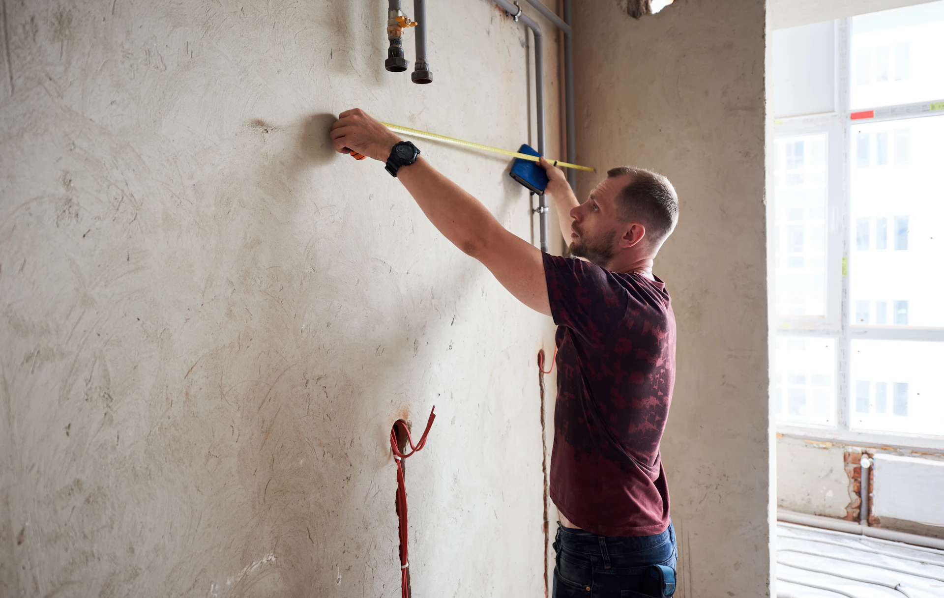 Professional tradesman measuring up a wall for a maintenance job